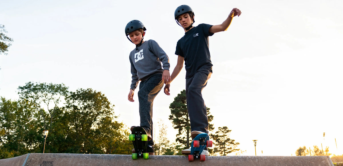 Two boys at skate ramp preparing to ride down on skateboards, showing active outdoor play that supports kids’ mood, sleep, and focus.