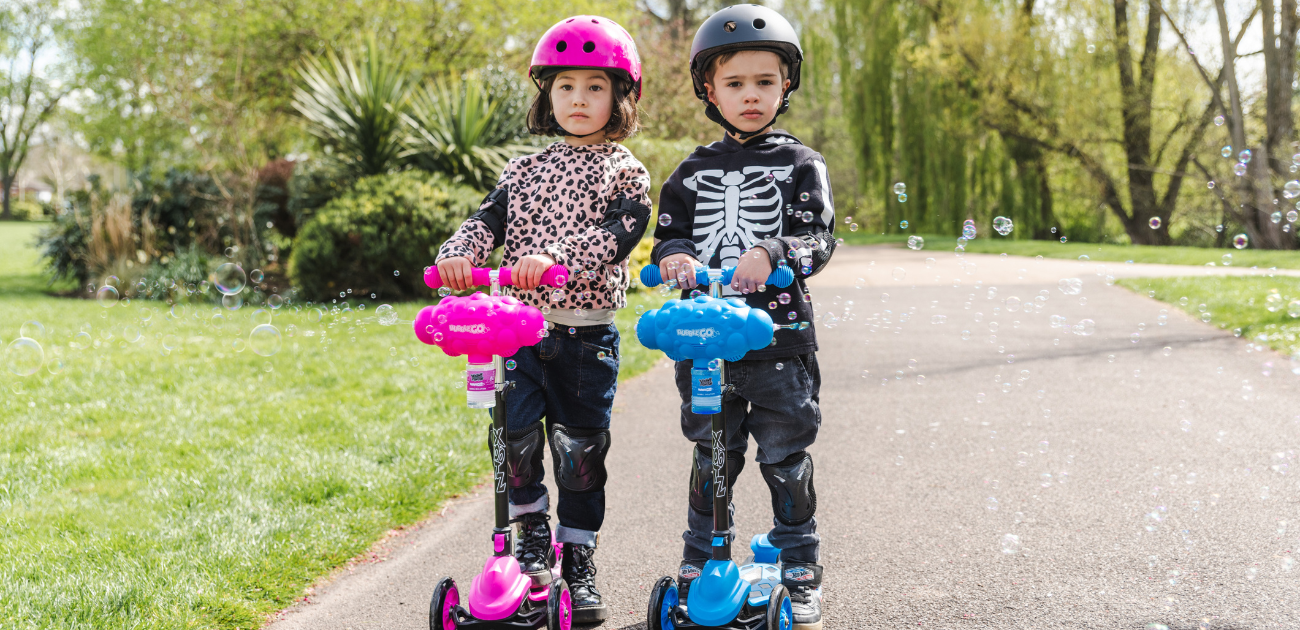 Two children riding Xootz scooters in a park, illustrating tips for teaching kids to ride.