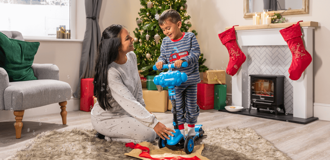 Child and mum unboxing a Xootz Bubble Go scooter on Christmas morning - the perfect ride-on gift for kids.