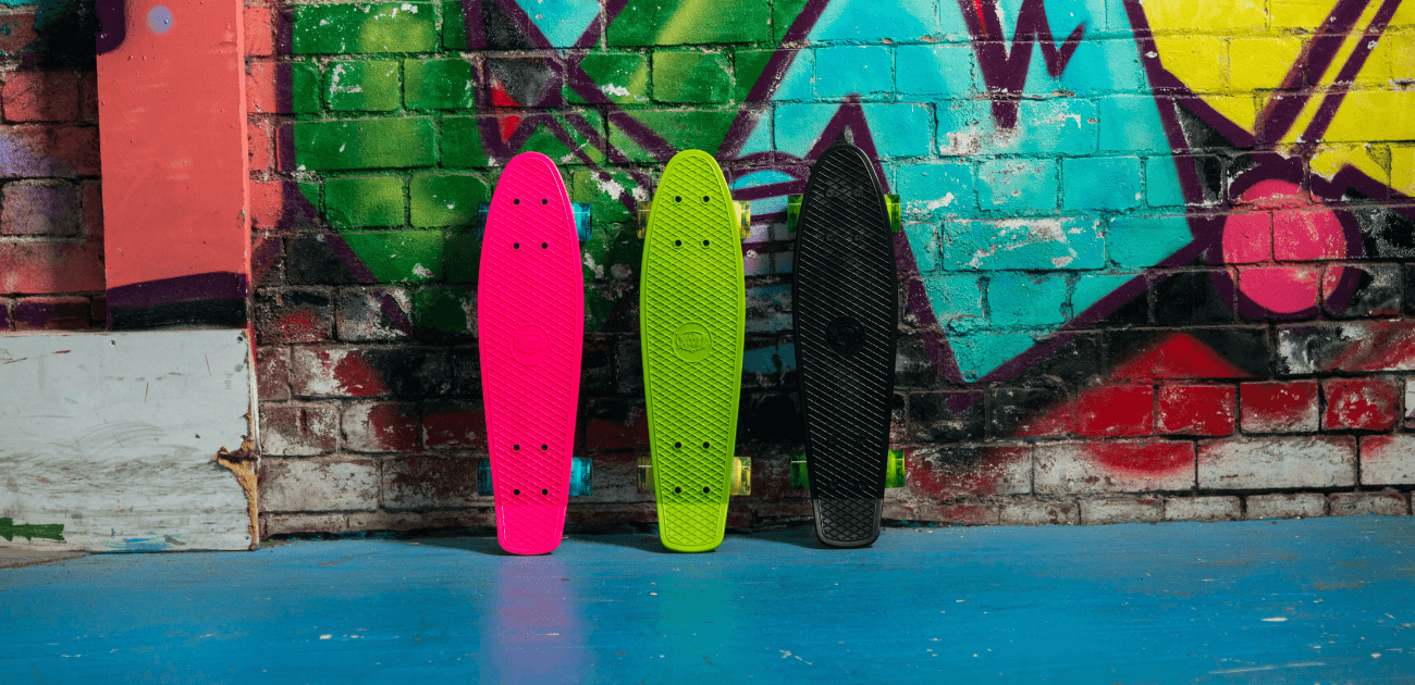 Urban-style photo of three skateboards and a graffiti wall - representing the fun and freedom of skateboarding.