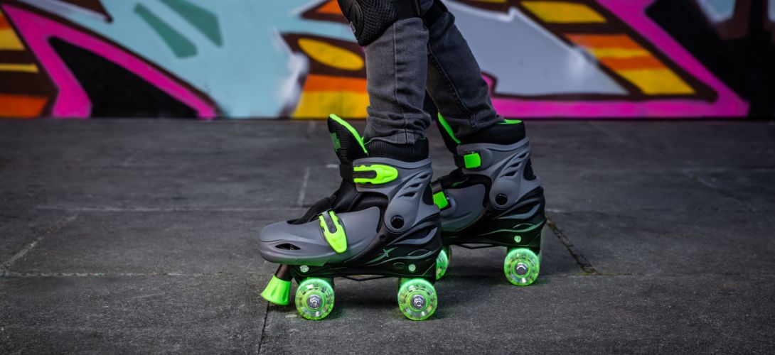 A photo of a pair of black & green quad skates against a graffiti background