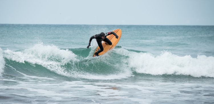 A man in a full winter wetsuit surfing